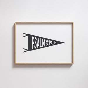 Könnte beinhalten: Ein schwarz-weißes Wimpel mit dem Text "PSALM & PALM" darauf gedruckt. Der Wimpel ist in einem hellen Holzrahmen gerahmt.
