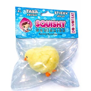 May include: A yellow, fluffy chick squishy toy in a clear plastic bag. The packaging features the text "Taba Squishy" and "Squishy Squishies" with a cartoon character. The toy has orange feet and a beak, and the packaging says "Do Not Eat".