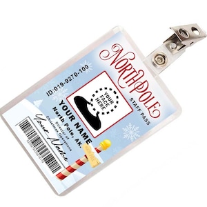 May include: A white plastic ID card with a blue background and snowflakes. The card has the text "North Pole Staff Pass" and "ID:019-9270-100". There is a space for a photo with the text "Your Face Here". The card also has the text "Your Name" and "North Pole, AK. Director of Christmas Operations".