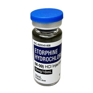 Puede incluir: Un vial de clorhidrato de etorfina (M-99) HCI Injection, con tapa azul. La etiqueta incluye "10mg/10mL" y "30mL Multiple-dose". El líquido dentro del vial es oscuro.