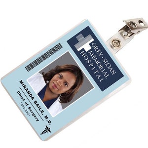 May include: A blue and white plastic ID badge with a photo of a woman and the text "GREY+SLOAN MEMORIAL HOSPITAL" and "MIRANDA BAILE, M.D. Chief of Surgery 7002-2901".