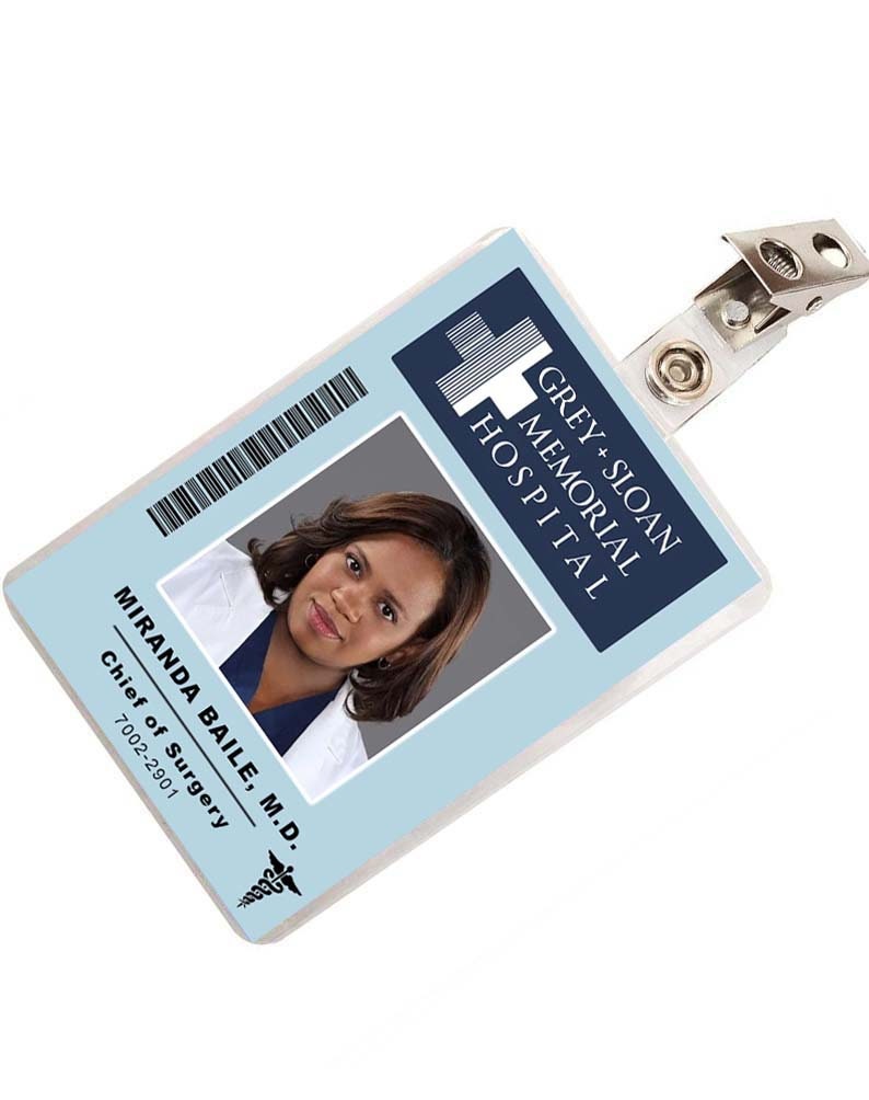 May include: A blue and white plastic ID badge with a photo of a woman and the text "GREY+SLOAN MEMORIAL HOSPITAL" and "MIRANDA BAILE, M.D. Chief of Surgery 7002-2901".