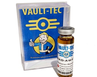 May include: A clear glass bottle with a brown liquid inside. The bottle has a silver cap and a blue and white label that says "Vault-Tec" and "Rad-Away Radiation Remedy". The bottle is sitting in front of a box with a blue and white label that says "Vault-Tec" and has a Vault-Tec logo.
