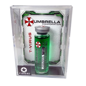 Może przedstawiać: Przezroczysta gablota zawiera fiolkę z zielonym płynem z napisem "T-VIRUS" i "UMBRELLA CORPORATION". Fiolka ma srebrną zakrętkę i czerwono-białe logo. Gablota ma czarno-białe logo z napisem "FIGHERO".