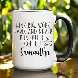 May include: White ceramic coffee mug with a black rim and handle. The mug has black text that reads "Think big, work hard, and never run out of coffee!" with a small coffee cup icon. The name "Samantha" is written below the text.