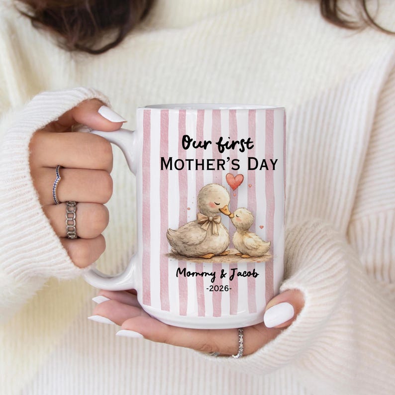 May include: White ceramic mug with pink vertical stripes, featuring the text "Our first Mother's Day" and a watercolor illustration of two ducks. The mug also includes the text "Mommy & Jacob -2026-".