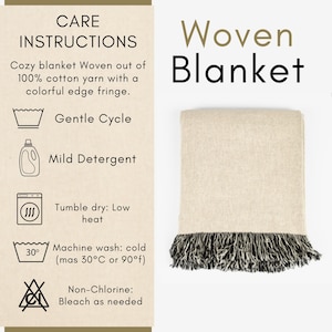 May include: A woven blanket with a cream-colored body and a black and white fringe. The blanket is made of 100% cotton yarn. The image also includes care instructions, such as gentle cycle and tumble dry low.