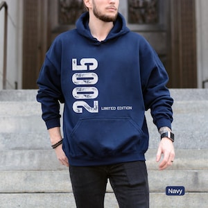Pu&ograve; includere: Felpa con cappuccio blu navy con l'anno "2005" stampato verticalmente in bianco, insieme alle parole "LIMITED EDITION". La felpa ha una tasca frontale e un cappuccio. Il colore &egrave; indicato come "Navy".