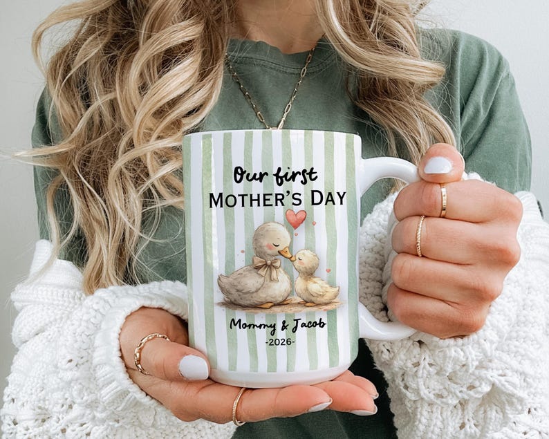 May include: White ceramic mug with a green striped pattern and the text "Our first MOTHER'S DAY". The mug features an illustration of two ducks and the text "Mommy & Jacob -2026-".