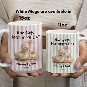 May include: Two white ceramic mugs, 15oz and 11oz, with handles. Each mug features a duck and duckling illustration with the text "Our first MOTHER'S DAY", "Mommy & Jacob -2026-". The larger mug has pink stripes, the smaller has green.