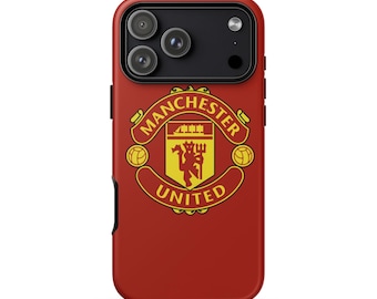 May include: A red phone case featuring the Manchester United logo. The logo is in yellow and red, with the words "Manchester United" in a curved banner. The case has a black camera module.