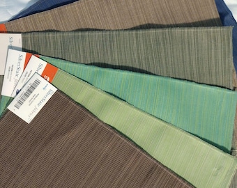 May include: A selection of fabric swatches in various colors, including blue, brown, green, and teal. Each swatch has a textured, striped pattern. The swatches are arranged in a fan shape, with labels visible on some.
