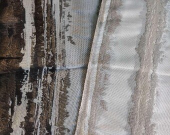 Op de afbeelding: Een textielstof met een gelaagd ontwerp met een opvallend gedeelte van donkerbruine en zwarte verticale abstracte penseelstreekpatronen naast een lichter, glinsterend zilver en grijs gedeelte met een zachte, getextureerde en licht verhoogde afwerking.
