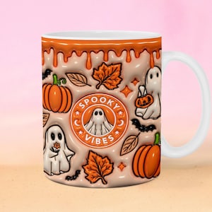 May include: White ceramic mug with a Halloween design. The mug features orange pumpkins, ghosts, and autumn leaves against a beige background with orange drips. The text "Spooky Vibes" is in a circular emblem.