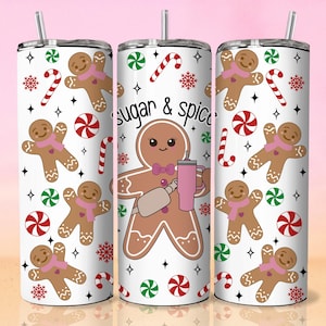 May include: White tumbler with a festive gingerbread theme. The design features gingerbread men, candy canes, and the text "sugar & spice." The tumbler includes a straw and a pink and white colour scheme, perfect for holiday drinks.