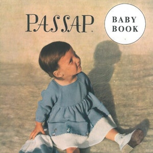 Könnte beinhalten: Ein kleines Mädchen in einem blauen Kleid mit weißem Saum und einer weißen Mütze sitzt auf einer weißen, flauschigen Oberfläche. Der Text "PASSAP BABY BOOK" ist in der oberen rechten Ecke des Bildes zu sehen.