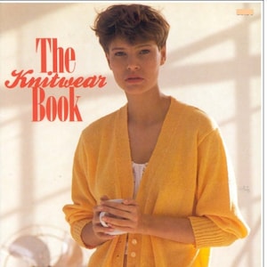 May include: A woman wearing a yellow cardigan with buttons and a white undershirt. The cardigan is knitted and has a V-neck. The text "The Knitwear Book" is visible in the top left corner of the image.