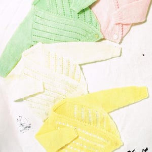 May include: Four knitted cardigans in different colors: green, white, yellow, and pink. The cardigans are made with a delicate openwork stitch and have a simple, classic design. The text "First Knit" is visible in the bottom right corner of the image.