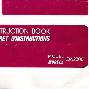 May include: A pink instruction booklet with the text "INSTRUCTION BOOK LIVRET D'INSTRUCTIONS MODEL CM2200" in white.