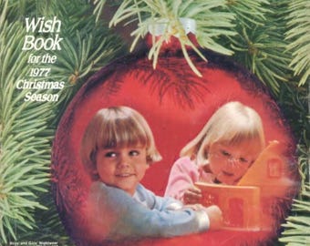 May include: A red Christmas ornament with two children inside. The girl on the right is holding a toy house. The ornament is surrounded by green pine branches. The text "Wish Book for the 1977 Christmas Season" is at the top of the image.