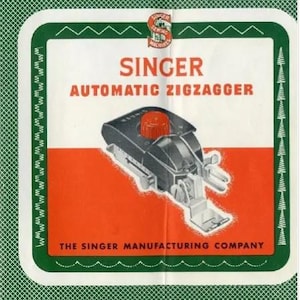 Könnte beinhalten: Vintage Singer Automatic Ziggagger-Aufsatz. Das Bild zeigt einen Retro-Nähmaschinenaufsatz mit rotem Knopf und silbernen Metallkomponenten. Der Text auf dem Bild lautet "SINGER AUTOMATIC ZIGZAGGER" und "THE SINGER MANUFACTURING COMPANY."