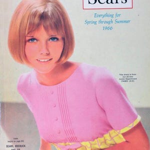Op de afbeelding: Een vintage Sears cataloguscover uit 1966 met een blonde vrouw in een roze jurk met gele geruite accenten. De catalogustitel luidt "Sears Everything for Spring through Summer 1966".