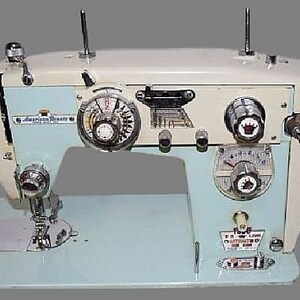 May include: A vintage white and light blue sewing machine with a silver bobbin case and a black foot pedal. The machine has a variety of dials and knobs, including a stitch length dial, a tension dial, and a reverse stitch lever. The machine also has a needle threader and a bobbin winder.