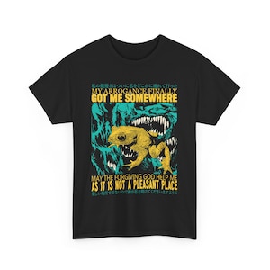 May include: Black t-shirt featuring a graphic of a yellow frog against a green background. The text on the shirt reads "My arrogance finally got me somewhere. May the forgiving god help me as it is not a pleasant place."