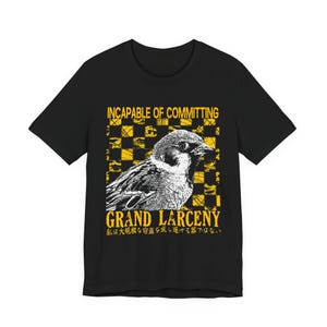 Könnte beinhalten: Ein schwarzes Kurzarm-T-Shirt mit einer gelb-weißen Grafik eines Spatzen, zentriert über einem gelben Karomuster. Der Text lautet INCAPABLE OF COMMITTING GRAND LARCENY und enthält japanische Schriftzeichen unter dem englischen Haupttext.