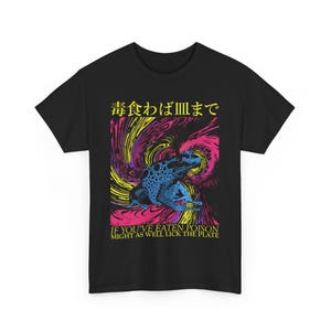 May include: Black t-shirt with a graphic of a blue and black frog against a swirling pink, yellow, and purple background. The shirt features Japanese text and the English phrase, "IF YOU'VE EATEN POISON MIGHT AS WELL LICK THE PLATE."