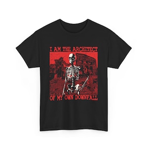 May include: Black t-shirt with a red graphic. The graphic shows a skeleton holding a staff in front of a ruined building. The text "I AM THE ARCHITECT OF MY OWN DOWNFALL" is printed above and below the graphic in red.