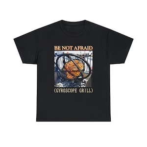 May include: Black t-shirt featuring a graphic of a gyro grill with the text "BE NOT AFRAID" above and "(GYROSCOPE GRILL)" below. The image shows a rotating grill with cooked meat.