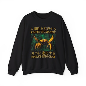Op de afbeelding: Zwart sweatshirt met een gele krab-afbeelding en de tekst "Reject Humanity, Evolve into Crab" in het Japans en Engels.