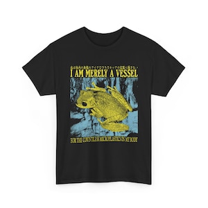 Op de afbeelding: Zwart t-shirt met een gele kikker afbeelding en de tekst "I AM MERELY A VESSEL FOR THE COUNTLESS MICROPLASTICS IN MY BODY". Het ontwerp bevat Japanse tekst en een blauwe achtergrond.