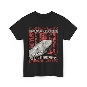 Könnte beinhalten: Schwarzes T-Shirt mit einer detaillierten Illustration eines Echsenkopfes und Text auf Englisch und Japanisch. Der englische Text lautet "THE COUNCIL OF VOICES GUIDES ME" und "I AM BUT A HUMBLE SERVANT".
