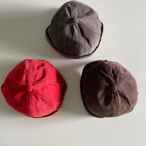 May include: Three corduroy bucket hats in different colours: grey, red and brown.