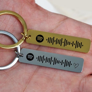 May include: Two silver and gold keychains with a Spotify logo and a barcode. The silver keychain has a small heart symbol.