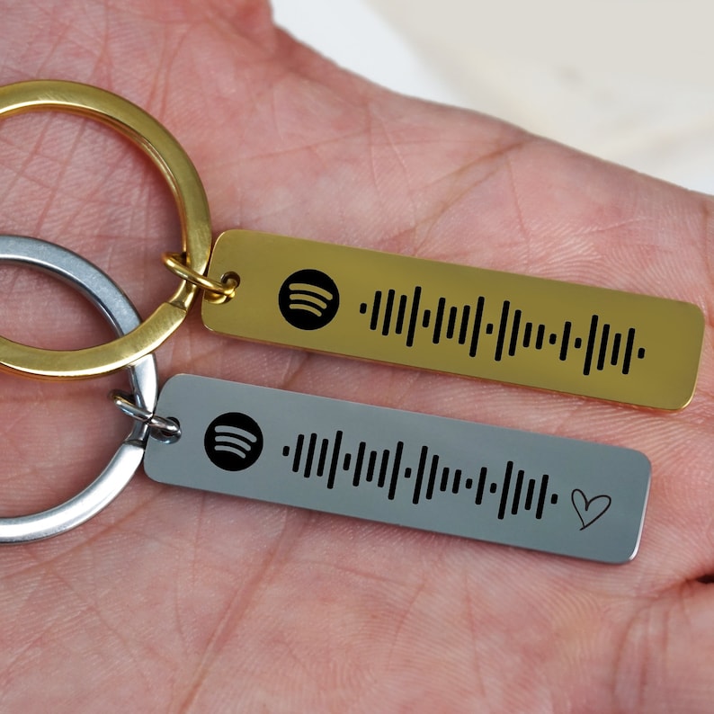May include: Two silver and gold keychains with a Spotify logo and a barcode. The silver keychain has a small heart symbol.