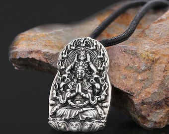 May include: Silver pendant necklace featuring a detailed depiction of a deity with multiple arms, sitting in a meditative pose. The pendant is surrounded by a decorative halo and sits on a cloud-like base.