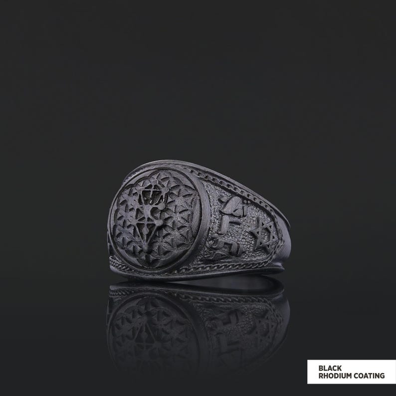 Op de afbeelding: Een zwarte ring met een gedetailleerd ontwerp met een geometrisch patroon en een ster. De ring is gemaakt van metaal en heeft een zwarte rhodium coating.