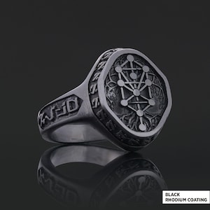 Op de afbeelding: Een zilverkleurige ring met een gedetailleerd ontwerp. De ring heeft een gegraveerd geometrisch patroon op de voorkant en zijkanten. De tekst "BLACK RHODIUM COATING" is rechtsonder zichtbaar.