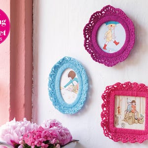 May include: Three crocheted picture frames with different colored borders and designs. The frames are hanging on a white wall. The frames are decorated with colorful illustrations of children.