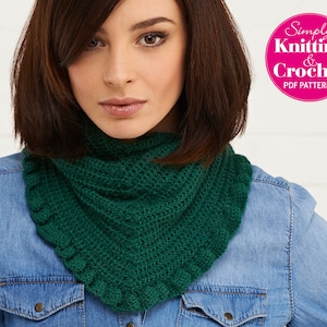 May include: A woman wearing a denim shirt with a green crocheted cowl neck scarf. The scarf has a scalloped edge.