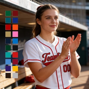 May include: White baseball jersey with red trim, the word "Team" in red script, and the number "00" in red. A color chart of various colors is on the left. The jersey is worn by a person.