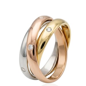 May include: A tri-colour interlocking ring featuring three smooth bands in yellow gold, rose gold, and white gold. The rose gold band is set with three small, round, clear sparkling diamonds embedded at intervals along the polished metal surface.