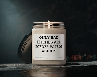 May include: A lit candle in a glass jar with a silver lid. The label reads "ONLY BAD BITCHES ARE BORDER PATROL AGENTS." The text below says "Infused with dedication, passion & a touch of badassery."