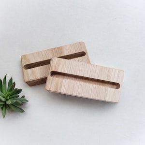 Könnte beinhalten: Zwei Holz-Telefonständer mit einem Schlitz zum Halten eines Telefons. Die Ständer sind aus hellbraunem Holz und haben eine natürliche Oberfläche.