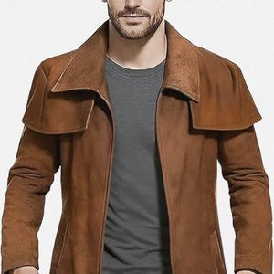 May include: A long, brown leather coat with a wide collar and a long, flowing design. The coat is worn over a gray shirt and blue jeans. The coat appears to be made of a soft, supple leather.