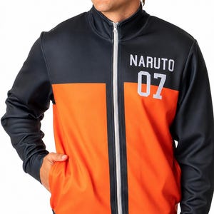 以下が含まれることがあります： 胸に「NARUTO」の文字と数字「07」がプリントされた、黒とオレンジ色のジップアップジャケット。 ジャケットは白いジッパー付きで、人が着用しています。