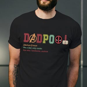 May include: Black t-shirt with a colorful graphic that says "DADPOOL" with a definition and a list of synonyms. The graphic includes the Avengers logo, Deadpool's mask, and Thor's hammer.